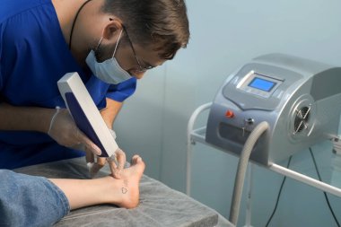 Dövmeyi silen lazer. Ezik, aşık ve kalbi kadınların ayağında kırmızı ve siyah renklerde. Eldivenli doktorun yakın çekim elleri. Gençlik aşkının ve hayal kırıklığının romantik dövmesi..