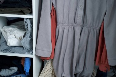 Raflarda farklı giysileri olan ve askılarda asılı kadın gardıropları. Depolama yöntemi, giysi depolama sistemi, soyunma odası..