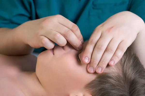頭蓋内科治療のセッション 医師セラピストによる10代の男の子の鼻の治療 頭蓋内科のセラピストは 男の子の鼻に触れ 病院で手で鼻のチェックを修正し 顔の側面図 — ストック写真