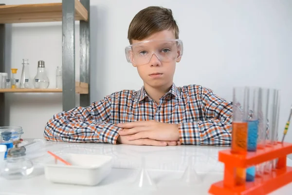 戴着防护眼镜的严重少年坐在化学实验室的桌旁 在线教育 家庭教育和科学概念 幼儿时期的科学活动 — 图库照片