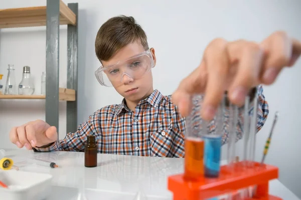 10代の男の子が化学実験をしている注射器を使ってチューブに赤い液体を注いでいます オンライン教育 ホームスクーリング 科学の概念 幼い頃の科学活動 — ストック写真