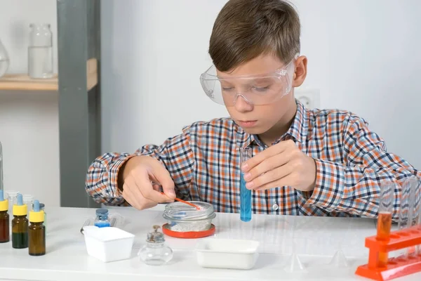 안경을 보호하는 소년은 튜브에 파란색 액체와 가루를 실험을 있습니다 온라인 — 스톡 사진