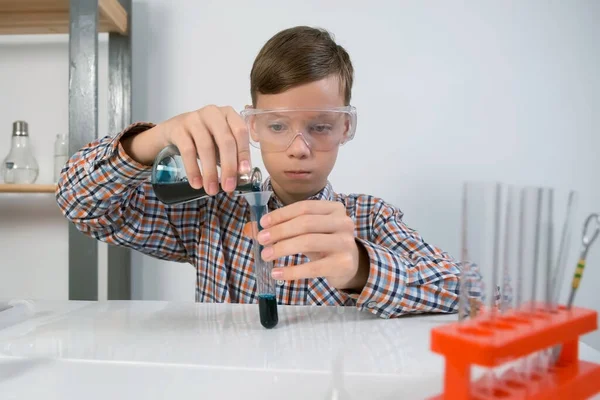 少年男孩在试管中把蓝色液体从瓶中倒入漏斗进行化学实验 在线教育 家庭教育和科学概念 幼儿时期的科学活动 — 图库照片
