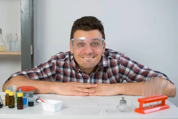疯狂快乐的人打算在家里做化学实验 他看着相机 微笑着 科学和幽默的概念 他戴着防护眼镜 脸上带着一副鬼脸 — 图库照片