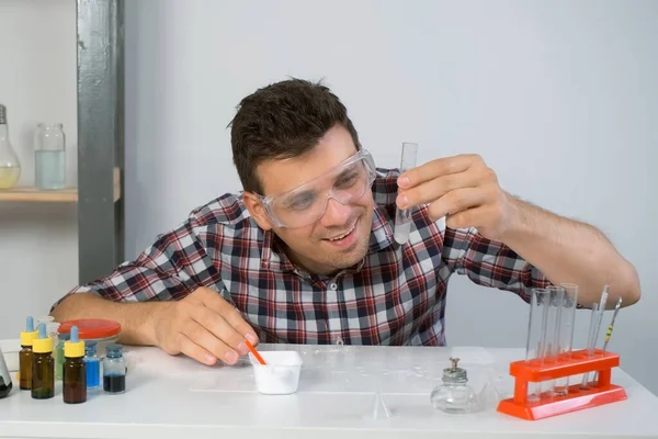 疯狂快乐的男人在家里用粉末和试管做化学实验非常有趣 科学和幽默的概念 他戴着防护眼镜 脸上带着一副鬼脸 — 图库照片