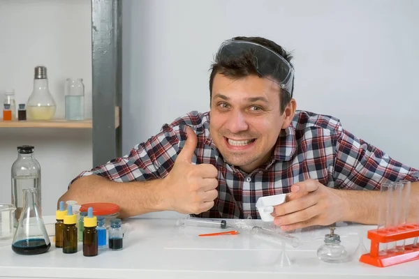 疯狂快乐的人在家里做化学实验 吃试剂 科学和幽默的概念 他戴着一副防护眼镜 脸上带着一副大拇指的样子 — 图库照片