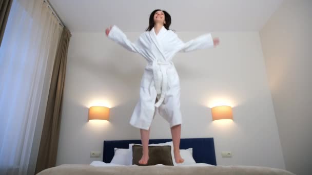 Beyaz Bornozlu Mutlu Esmer Kadın Otel Odasında Gülümsüyor Yatağa Atlıyor — Stok video