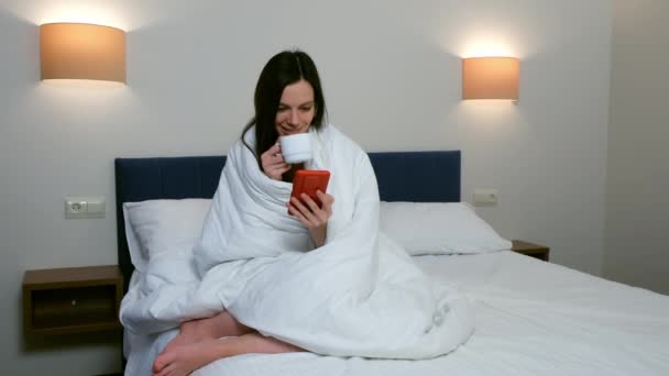 Brunette Vrouw Drinkt Thee Koffie Sms Smartphone Zittend Bed Rust — Stockvideo