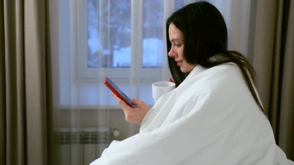 Brunette Jonge Vrouw Drinkt Koffie Leest Nieuws Smartphone Zittend Bed — Stockvideo