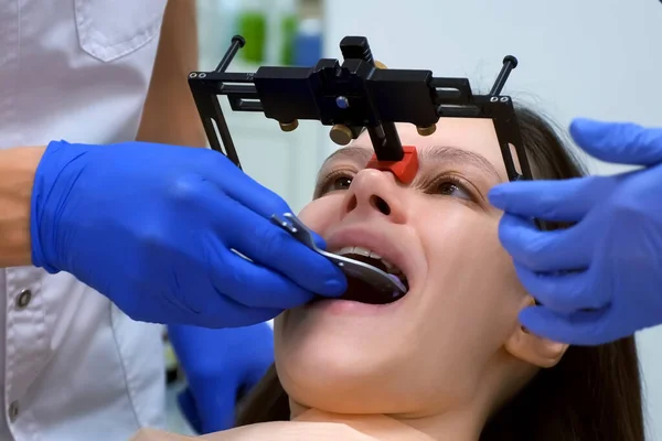 Orthodontist installs dental facebow on woman face, prosthetics. Orthodontic treatment in dentistry, dental prosthetics. Bite and joint, occlusion correction before installing veneers crowns.