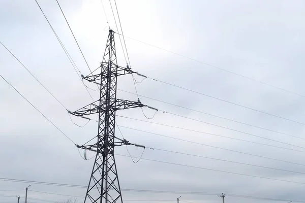 stock image High voltage electric tower with wires on overcast sky background. Transmission power line. Parts of electrical equipment and high voltage power line insulators.