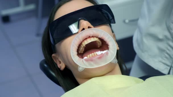 为安装防毒面具准备牙齿 牙科妇女 嘴里衔着牵引器 太阳镜在等着医生 牙科治疗 假肢的概念 牙齿矫正疗法 — 图库视频影像