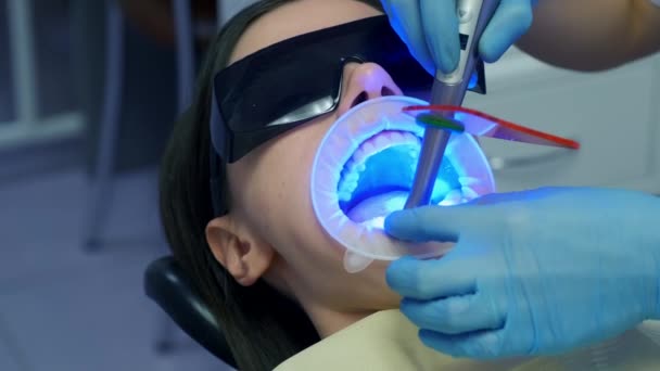 歯医者は歯科医院でUvランプを使用して歯の女性の静脈とセラミック冠を固定しています 歯科治療 義歯の概念 整形外科医の治療 — ストック動画