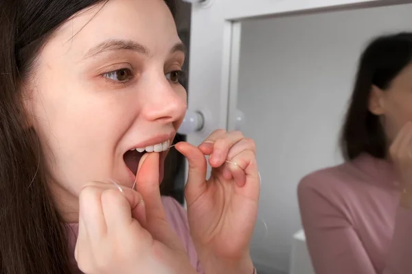 Aynanın Önündeki Genç Kadının Portresi Beyaz Dişlerini Diş Ipiyle Temizliyor — Stok fotoğraf