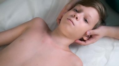Kraniosakral terapi seansı, genç çocukların kafa ve boyun arkasını bir doktor terapist tarafından tedavi etmek. Kraniosakral terapist çocukların kafalarına dokunuyor ve hastanede omurgalarını düzeltiyor. Çocuk kanepede yatıyor..