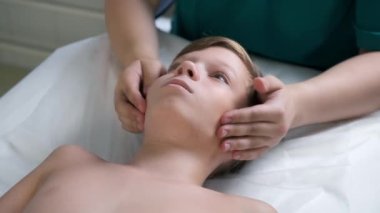 Kraniosakral terapi seansı, ergen çocukların çene ve boyun tedavisi bir doktor terapisti tarafından. Kraniosakral terapist çocukların yanaklarına dokunuyor ve hastanedeki çene düzeltmelerini elle kontrol ediyor..