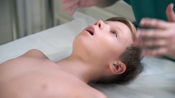 頭蓋内科治療のセッション 医師のセラピストによって10代の男の子顎の治療 頭蓋骨療法士は少年たちの頬に触れ 病院で顎の正確さをチェックします — ストック動画