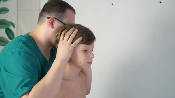 颅骨治疗 由医生治疗青少年脊柱 颅骨治疗师触摸男孩的头部和身体 矫正他在医院的脊柱姿势 — 图库视频影像
