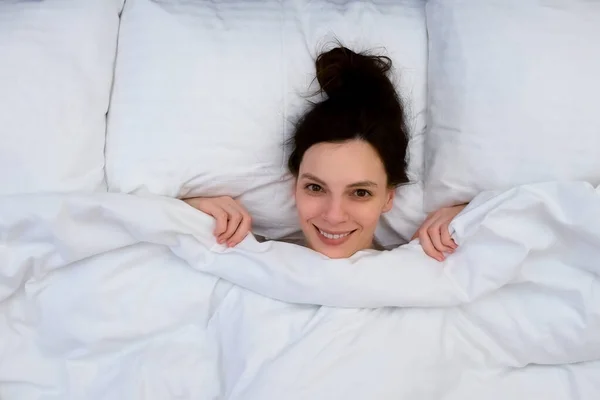 Улыбающаяся Привлекательная Юная Брюнетка Прячется Одеялом Лежа Утром Постели Белом — стоковое фото