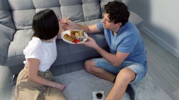 Młoda Szczęśliwa Para Mężczyzna Kobieta Sushi Bułki Razem Salonie Siedzą — Wideo stockowe