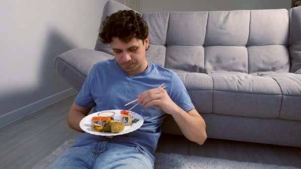 Portrait Jeune Homme Souriant Mange Des Rouleaux Sushi Dans Salon — Video