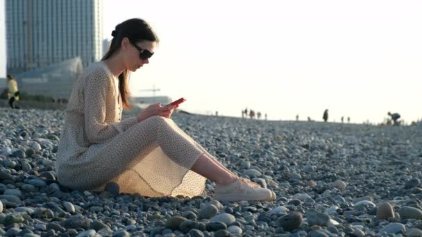 Mulher Pensativa Que Navega Smartphone Sentado Costa Mar Seixos Cidade — Vídeo de Stock