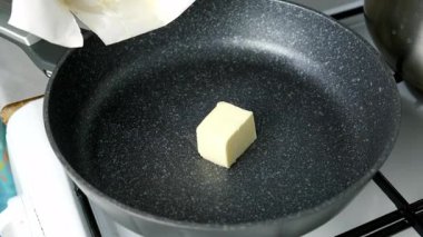 Kızartma tavasında tereyağı pişiren kadın ahşap spatulayla karıştırıyor. Isıtma tereyağı küpleri yemek hazırlıyor. Mutfak aşçısı yemek tarifi malzemelerini hazırla. Sağlıklı beslenme.