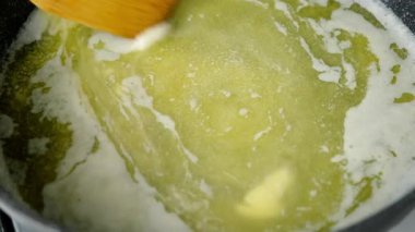 Kızartma tavasında tereyağı pişiren kadın ahşap spatulayla karıştırıyor. Tereyağı ısıtma tabağı. Mutfak aşçısı yemek tarifi malzemelerini hazırla. Sağlıklı beslenme.