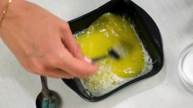 Erimiş tereyağına tuz ekleyen bir kadın. Evde çatalla karıştırılmış tereyağı pişiriyor. Yemek hazırlıyorum. Mutfak mutfağı ev yemeği tarifi malzemeleri. Sağlıklı beslenme hazırlığı.