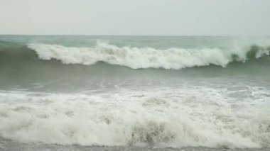 Deniz fırtınası, ezici dalgaların gücü. Su, doğa ve deniz manzarası. Bulutlu havada köpüklü. Suyun, doğanın ve deniz manzarasının gücü. Kıyı şeridine doğal büyük dalgalar sıçrıyor..