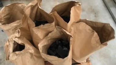 Kömür kömürü, fabrika üretim hattında kağıt torbalara doldurulmuş. Endüstriyel kömür imalatı, fabrika atölyesindeki modern ekipman otomatik işlem.