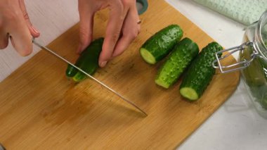 Salatalık kesmek için salatalık kesen kadın mutfaktaki ahşap tahtada salatalık pişirmek için, eller yakın çekim, üst manzara. Mutfak, aşçılık, aşçılık ev yemeği, yemek tarifi, malzeme konsepti..