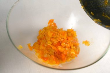 Ev hanımı kızartma tavasındaki kızarmış soğan domateslerinden sos pişirip mutfaktaki cam kaseye koyuyor. Mutfak teknikleri, ev yapımı sağlıklı yemek hazırlama, yemek pişirme, mutfak, baharat..