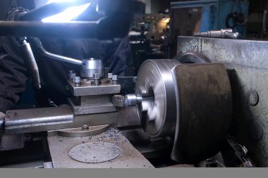 Metal işçisi atölyedeki torna makinesinde çalışıyor. Fabrika zemininde dönen metal parçası. Metalurji endüstrisi, otomatikleştirilmiş makine üretimi.