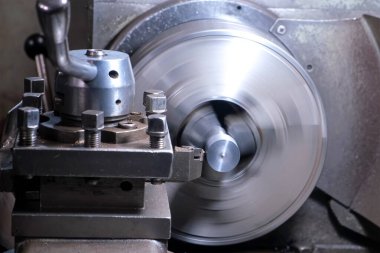 Otomatik torna makinesi fabrika atölyesinde metal parçaları döndürüyor ve şekillendiriyor. Metal parçacıklar parça parça uçuyor. Metalurji endüstrisi, otomatikleştirilmiş makine üretimi.