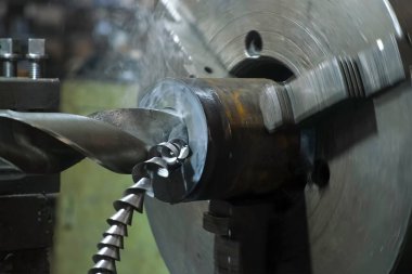 Torna makinesinin delme detaylarını kesen yakın çekim metal talaşları. Metalurji endüstrisi, otomatikleştirilmiş makine üretimi. Yeni metal parçaları oluşturma süreci.