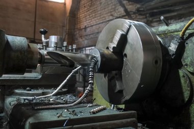 Sanayi torna makinesi santralde dönen metal silindir detayı. Kıvırcık yay metal talaşı. Metal endüstrisi, otomatik makine üretimi. İşçi soğutma sistemi soğutucu döküyor.