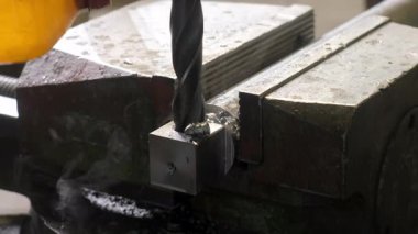 Fabrikada dönen matkapla metal sondaj yapan endüstriyel makineler. Kıvırcık yay metal talaşı. Metal endüstrisi, otomatik makine üretimi. İşçi soğutma sistemi soğutucu döküyor.