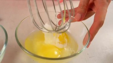 Kadın şekeri cam kasede yumurtalarla karıştırıyor mutfakta turta kurabiyeleri pişiriyor. Yemek tarifi mutfağı malzemesi. Pişirme, tatlı hazırlama, ev yapımı yemek. Kurabiye hamuru yapmak.