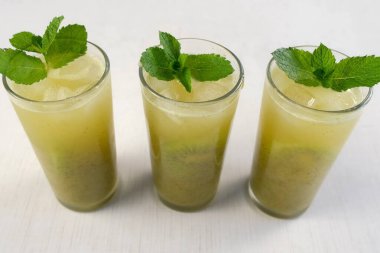 Taze yeşil kivili limonata, naneli yapraklar ve evde buzlu bardaklar. Yemek tarifi, profesyonel aşçılık. Lezzetli meyve tatlısı hazırla. Ev yapımı içecek..