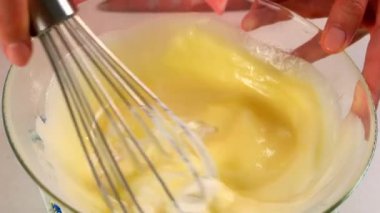 Turta yapmak için yemek pişiren kadın yumurtaları karıştırıyor, çırpıcıyı kullanarak kremayı kaseye koyuyor. Yemek tarifi mutfağı malzemesi. Pişirme, tatlı hazırlama, ev yapımı taze yemek. Taze yemek pastanesi yap..