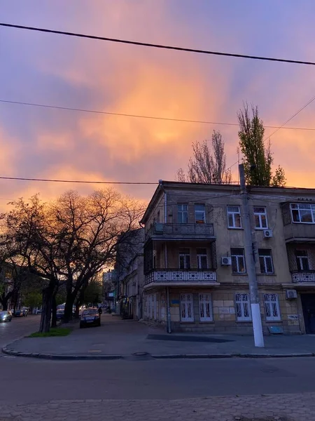 中央オデッサの小さな通りの古代の家の上の日没で虹色の色で燃える空の幻想的な自然写真 — ストック写真