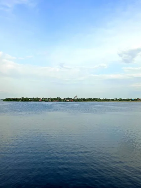 Samara Nehri 'nin durgun su yüzeyinin panoraması, ufuktaki uzak adaların arka planında, bulutlu, güneşli gökyüzünü yansıtıyor..