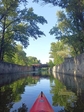 Asılan ağaçların gölgesinde yapay olarak oluşturulmuş kıyı duvarlarıyla çevrili su kanalı boyunca seyahat edin..