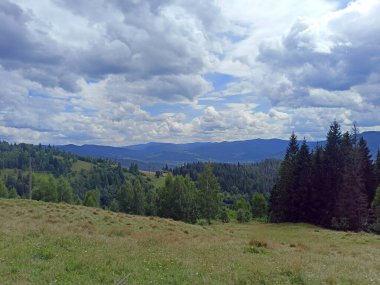 Gökyüzünün eşsiz bir manzarası Ukrayna Karpatlarının sayısız mavi sırtları üzerinde çeşitli şekil ve renklerle kaplıydı..