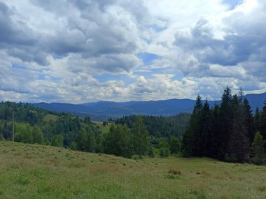 Gökyüzünün eşsiz bir manzarası Ukrayna Karpatlarının sayısız mavi sırtları üzerinde çeşitli şekil ve renklerle kaplıydı..