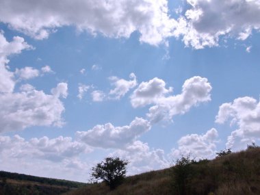 Güneş ışınlarıyla aydınlanan yaz bulutlarının doğal manzarası mavi gökyüzünün arka planına karşı..