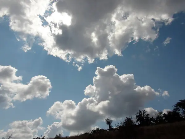 stock image Natural landscape of summer clouds illuminated by the sun's rays against the background of the blue sky.