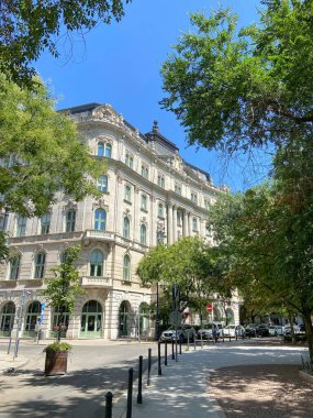 Ortaçağ kaldırım taşları boyunca, ağaçların gölgesinde, Macar başkentinin restore edilmiş antik binalarının arka planında uzanan huzurlu yaya yolları manzarası..