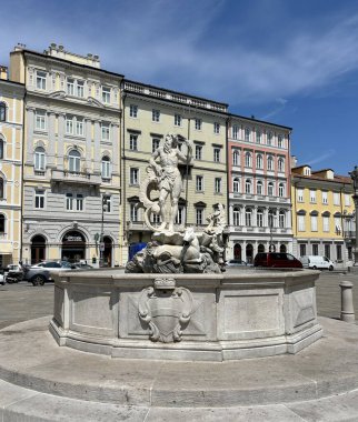 Trieste 'deki Piazza della Borza' daki çeşmenin üzerindeki deniz tanrısı Neptün 'ün heykeli yaz güneşinin parlak ışınlarının altında..